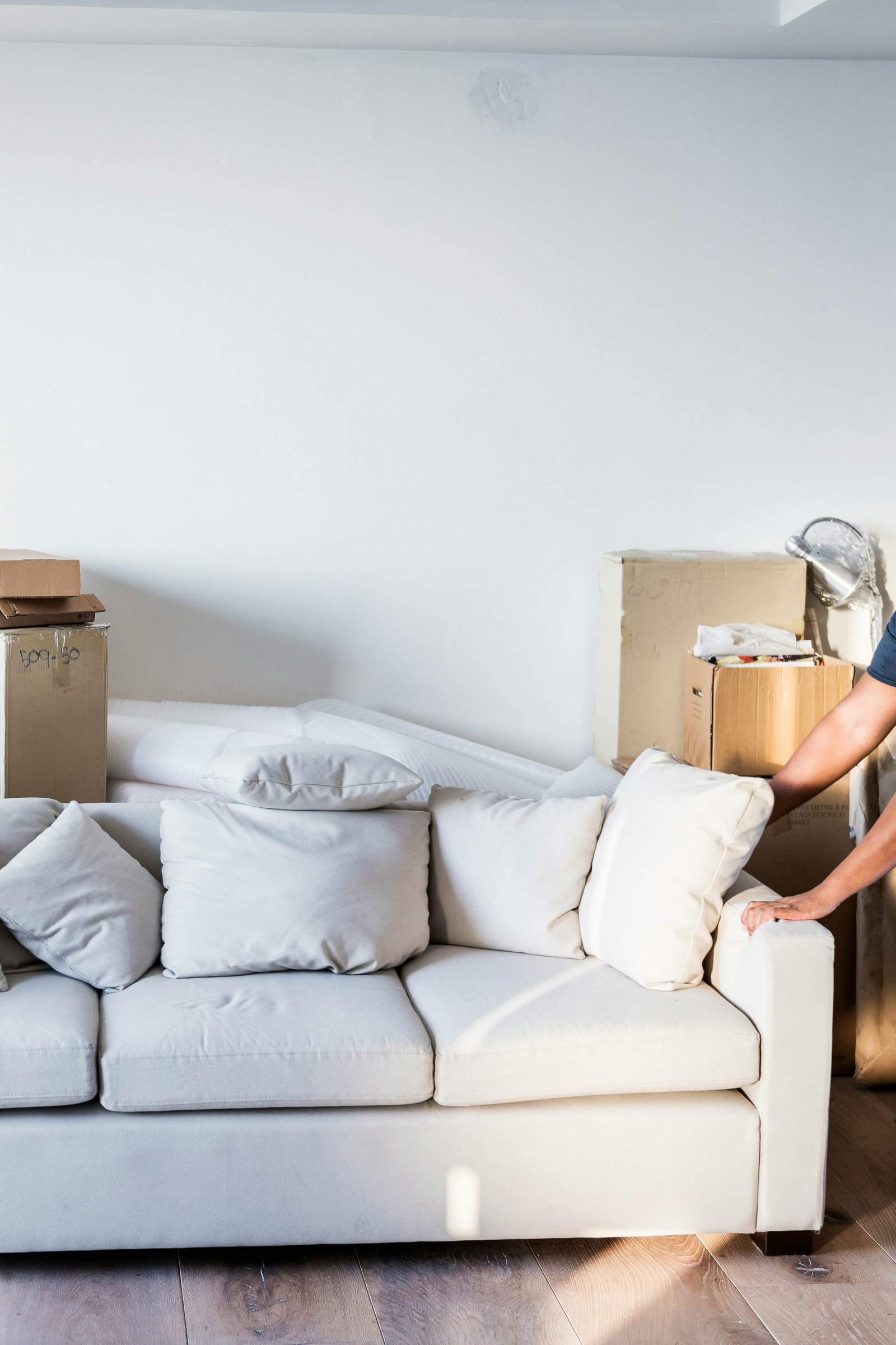 A Person Pushing A Couch With Moving Boxes Nearby
